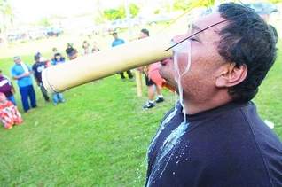 Tuba contest: Vince Naputi spills out a lot of tuba in the no-hand tuba drinking contest during Sunday's San Isidro fiesta celebration in Malojloj. (Jonathan Abella/For Southern Weekly)